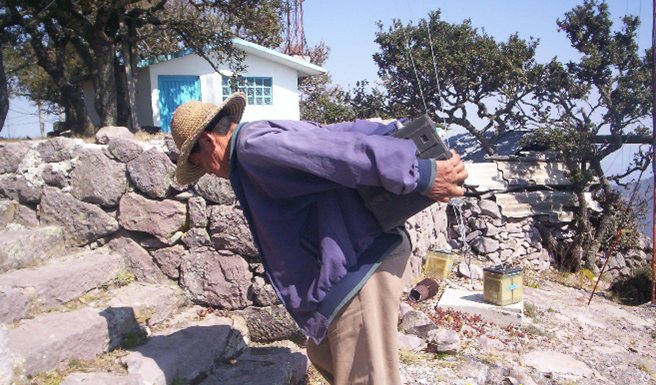 Don Epifanio cargando una batería de trailer para la planta generadora de energía eléctrica